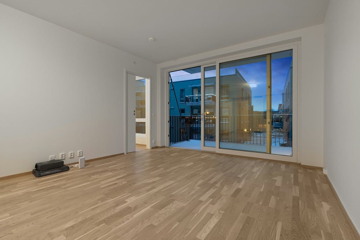 A bright, empty living room with sliding balcony doors